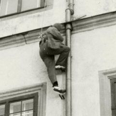 Ein Mann klettert an einer Regenrinne eine Hauswand hoch