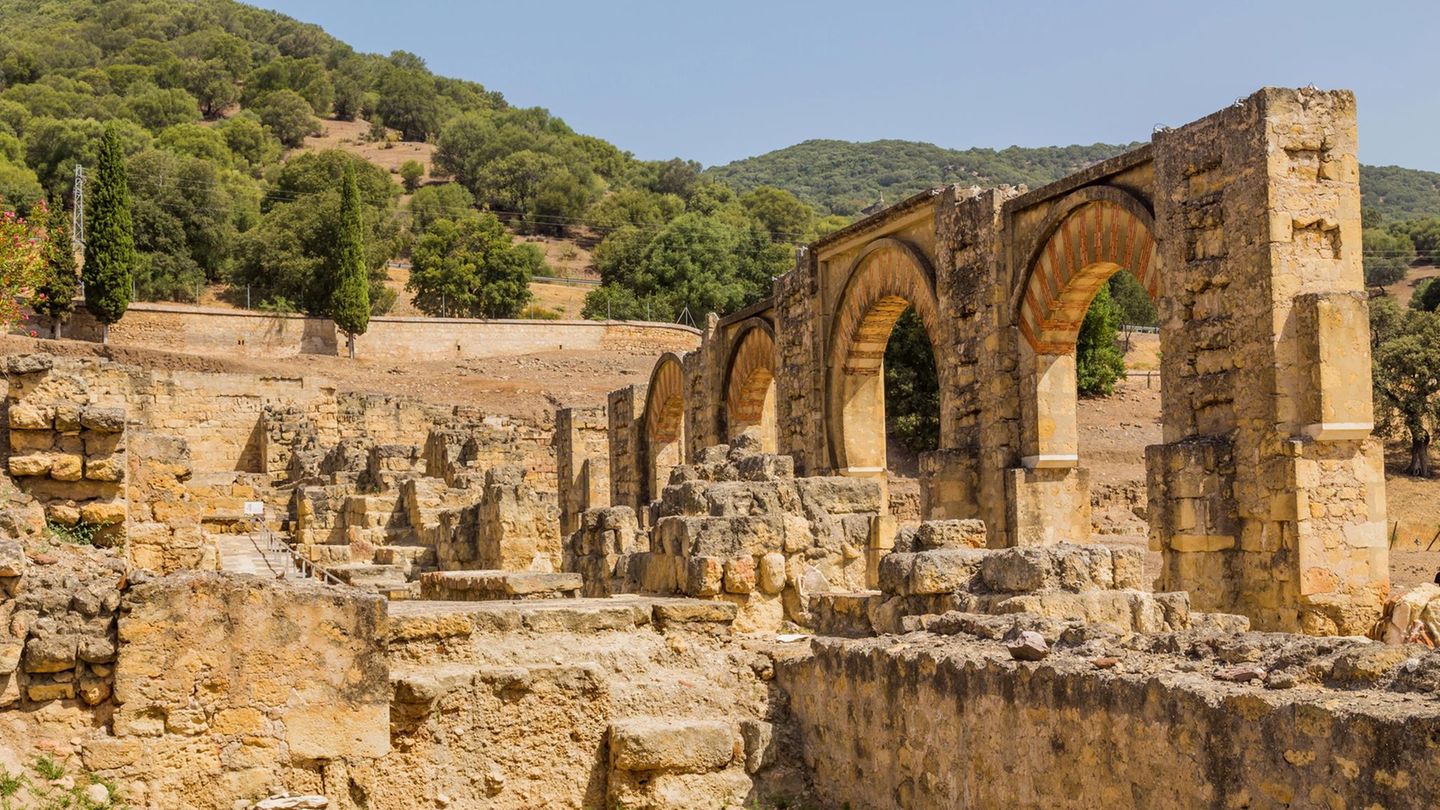 Ruinen der Palaststadt Madinat al-Zahrā aus hellem Gestein. Auf der rechten Seite vier Torbögen mit roten Verzierungen.