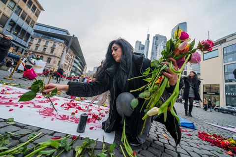Eine Frau legt auf einer Kundgebung gegen das Regime im Iran auf dem Rathenauplatz Rosen nieder
