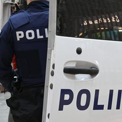 Ein Polizist in Finnland steht neben einem Polizeifahrzeug