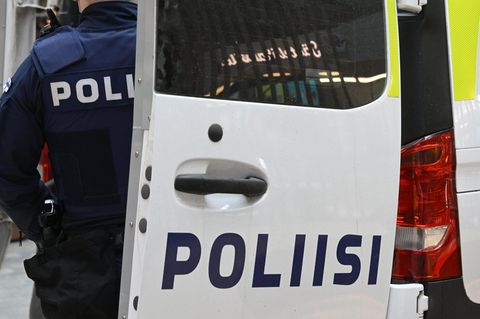 Ein Polizist in Finnland steht neben einem Polizeifahrzeug