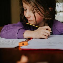 Ein Mädchen schreibt mit einem Bleisitft