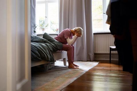 Ruhe: eine Pflegekraft sitzt erschöpft auf ihrem Bett