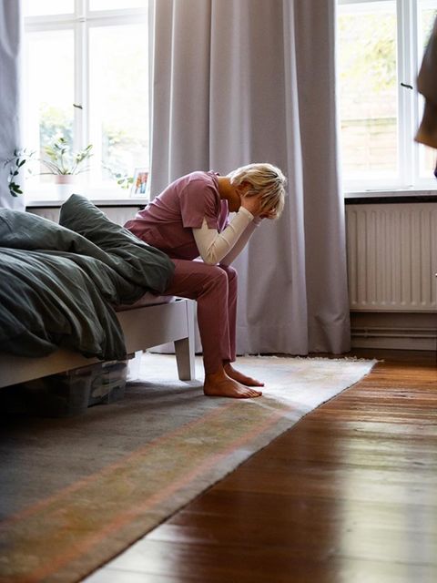 Ruhe: eine Pflegekraft sitzt erschöpft auf ihrem Bett