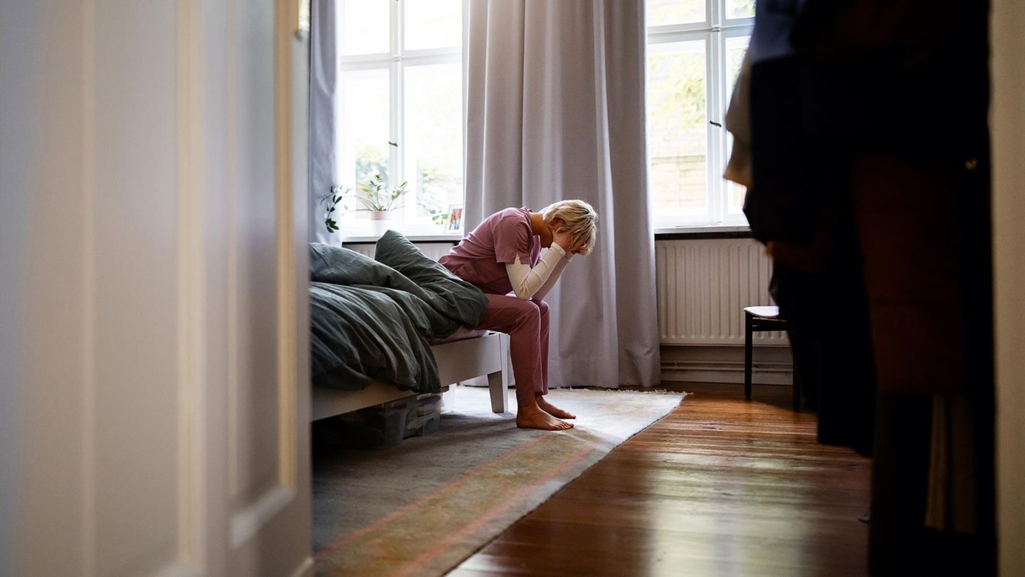 Ruhe: eine Pflegekraft sitzt erschöpft auf ihrem Bett