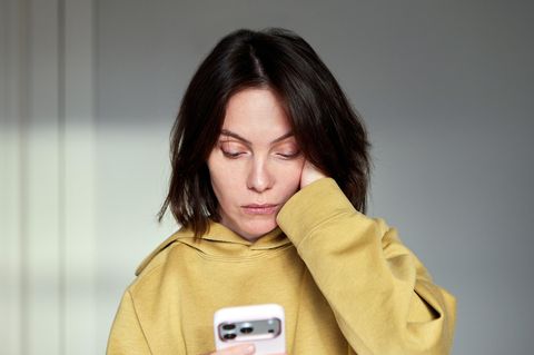 Handynacken: Frau blickt auf Handy