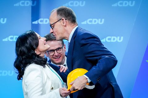 Friedrich Merz mit einem gelben Bauarbeiterhelm in der Hand und Gitta Connemann, dahinter CDU-General Carsten Linnemann