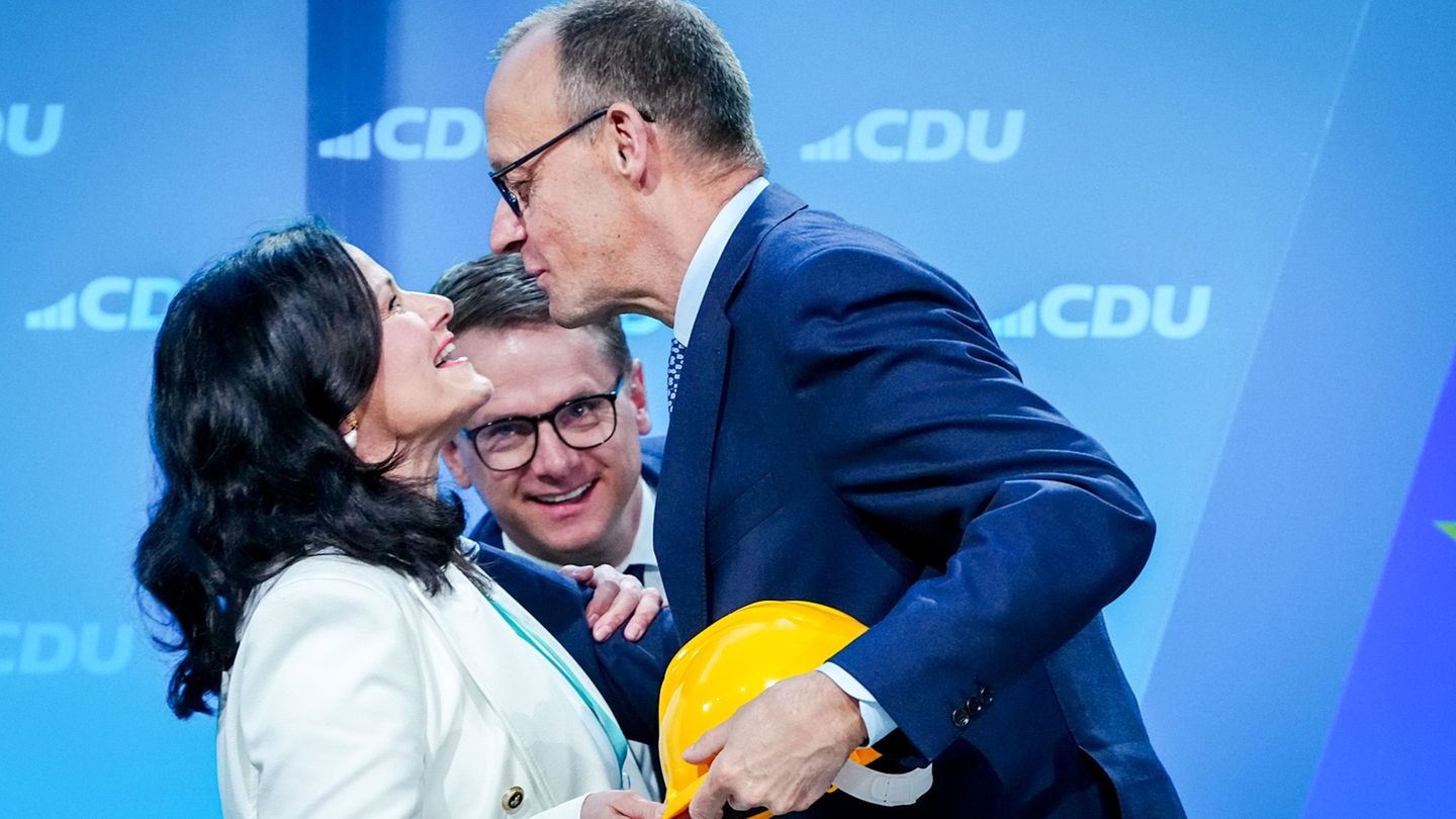 Friedrich Merz mit einem gelben Bauarbeiterhelm in der Hand und Gitta Connemann, dahinter CDU-General Carsten Linnemann