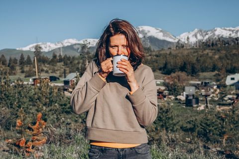 Eine Frau schlüft an einem Kaffee