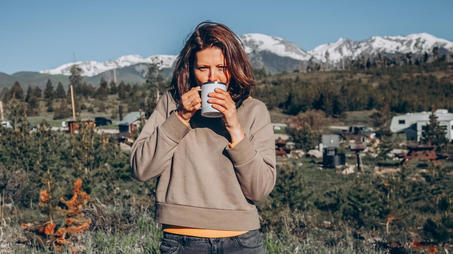 Eine Frau schlüft an einem Kaffee