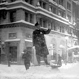 Ein Polizist steht auf einem Haufen Schnee. Schneefall umtost ihn
