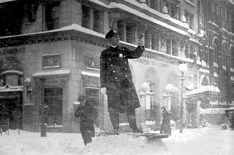 Ein Polizist steht auf einem Haufen Schnee. Schneefall umtost ihn