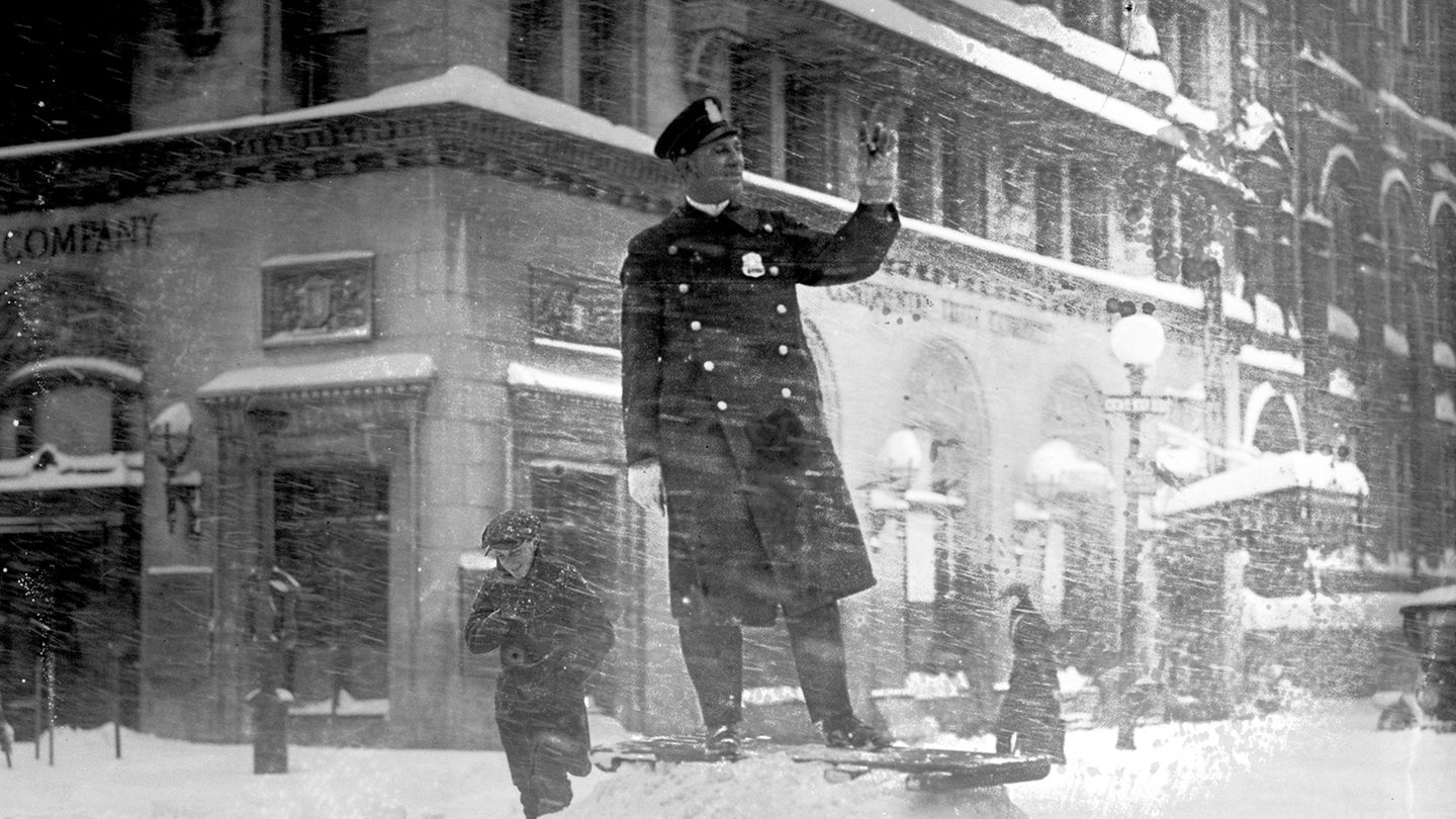 Ein Polizist steht auf einem Haufen Schnee. Schneefall umtost ihn