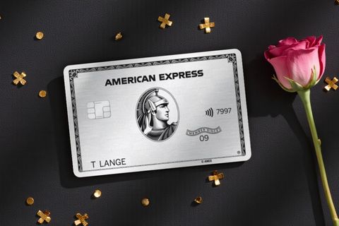 American Express Platinum Card auf dunklem Untergrund mit dekorativer Blume daneben