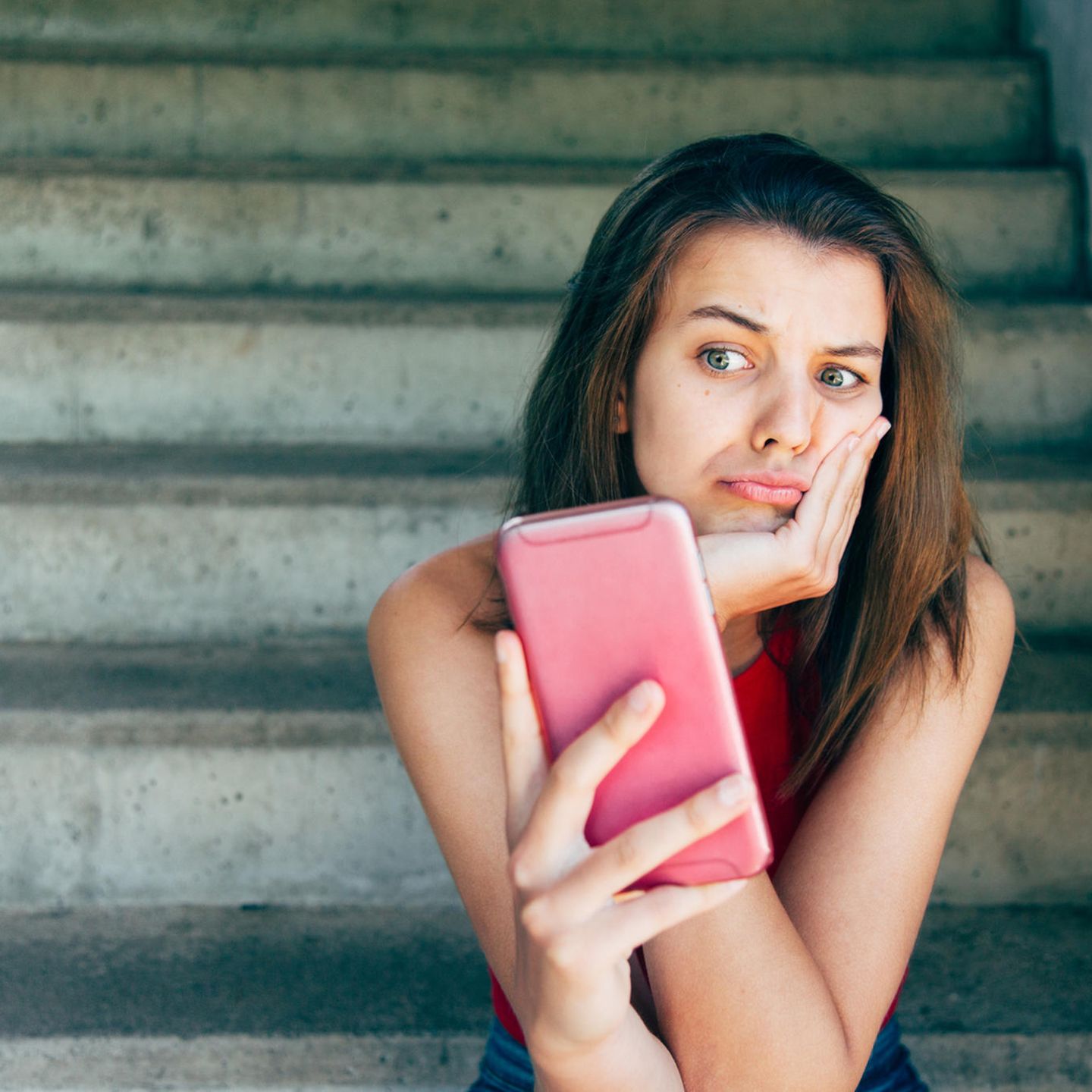 Eine Frau schaut genervt auf ihr Smartphone – geht es um Whatsapp?