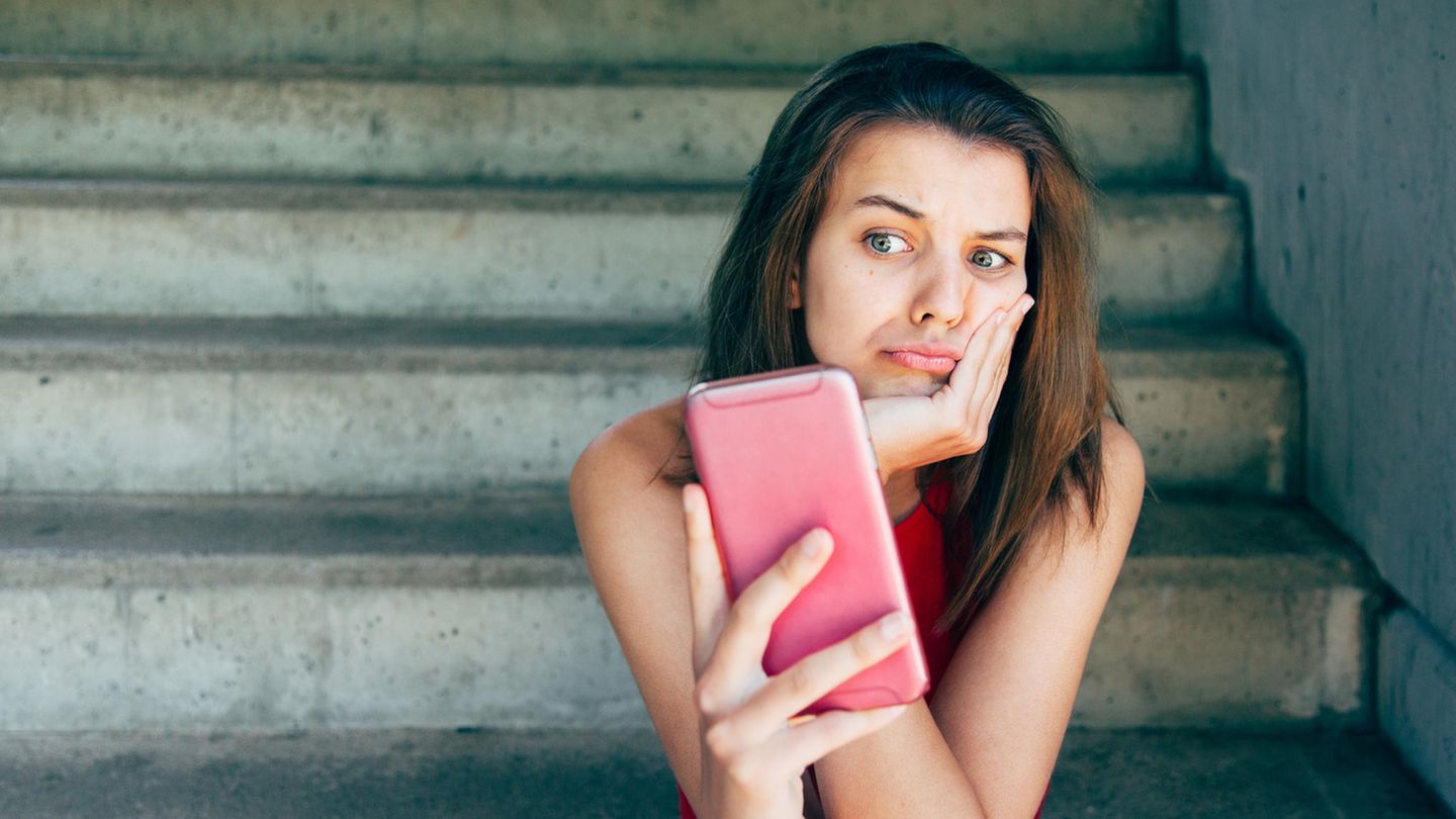 Eine Frau schaut genervt auf ihr Smartphone – geht es um Whatsapp?