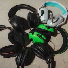 Fünf Gaming-Headsets hängen über einen Bildschirm