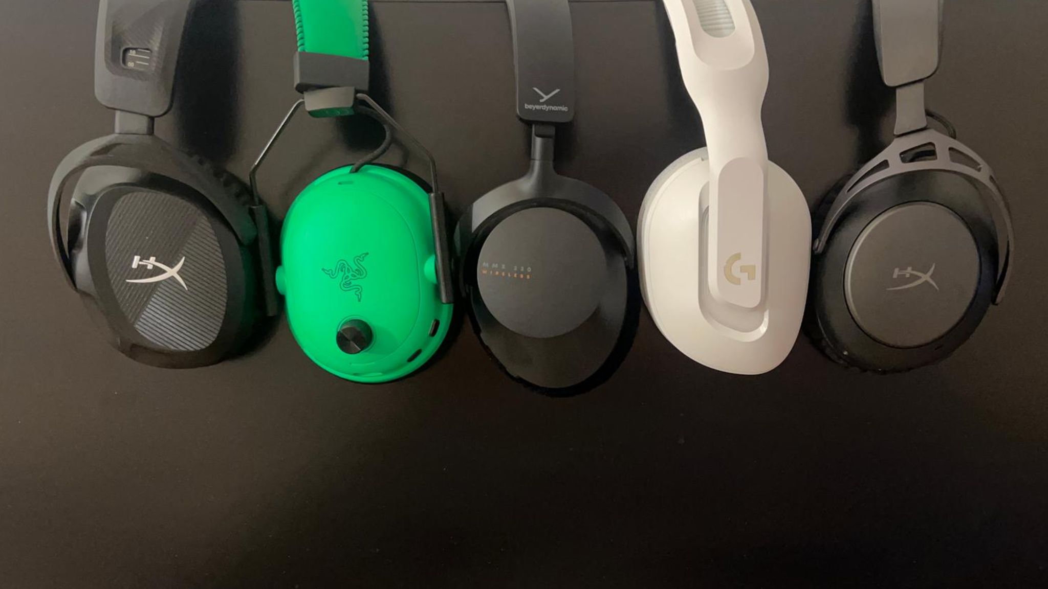 Fünf Gaming-Headsets hängen über einen Bildschirm