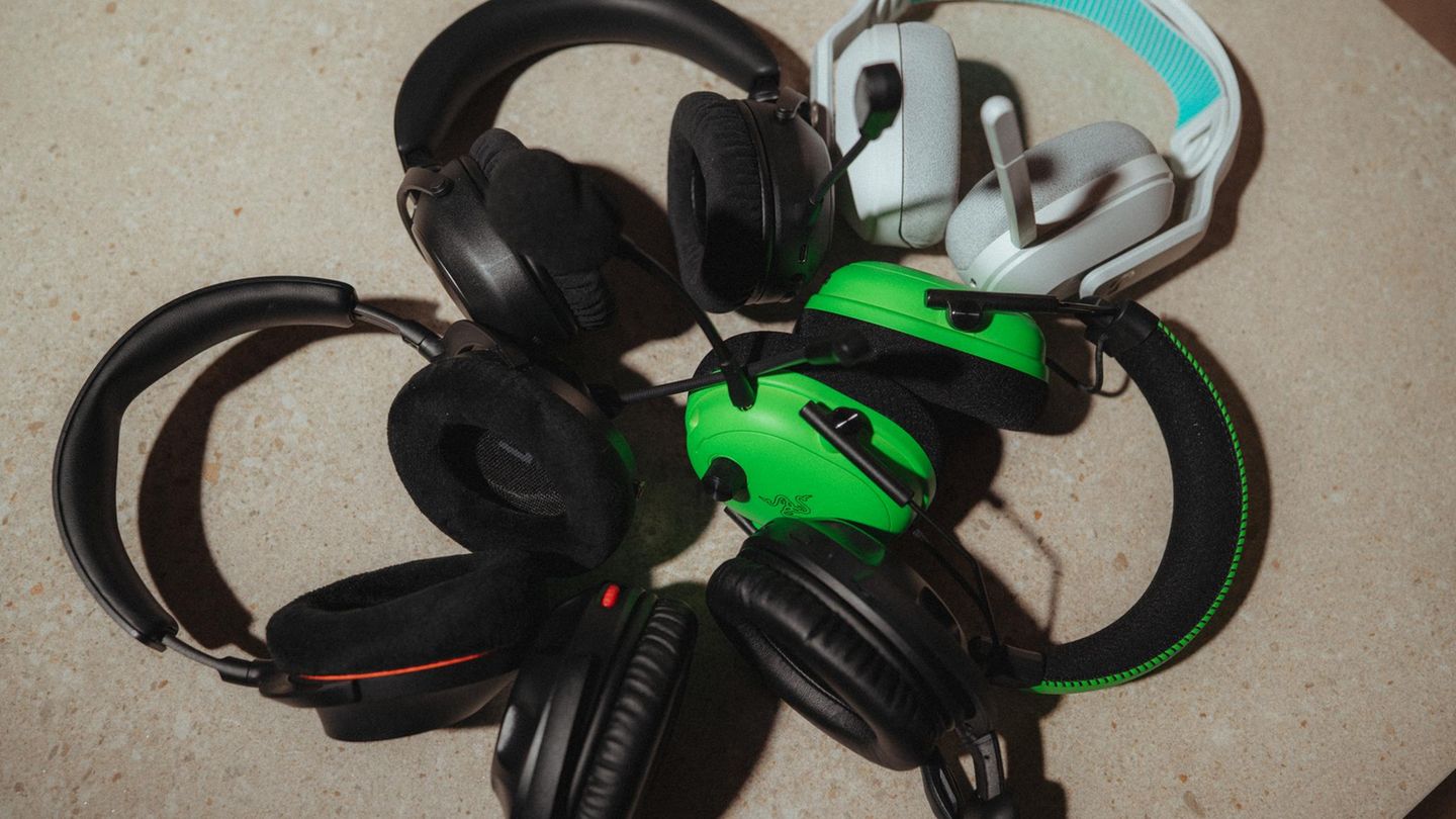 Fünf Gaming-Headsets hängen über einen Bildschirm