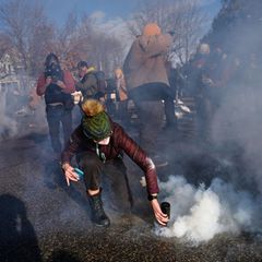 Die Proteste ziehen sich über Tage hin, weil ICE kein Einlenken bei den Razzien zeigt. Eine Demonstrantin versucht, eine Tränengasgranate zu entfernen, die Bundesbeamte in die Menge schießen. Die Stimmung heizt sich weiter auf. Aus Washington heißt es: Das Justizministerium lehnt eine Untersuchung des Vorfalls ab. US-Vizepräsident J.D. Vance sagt, Goods sei selbst schuld an den Schüssen