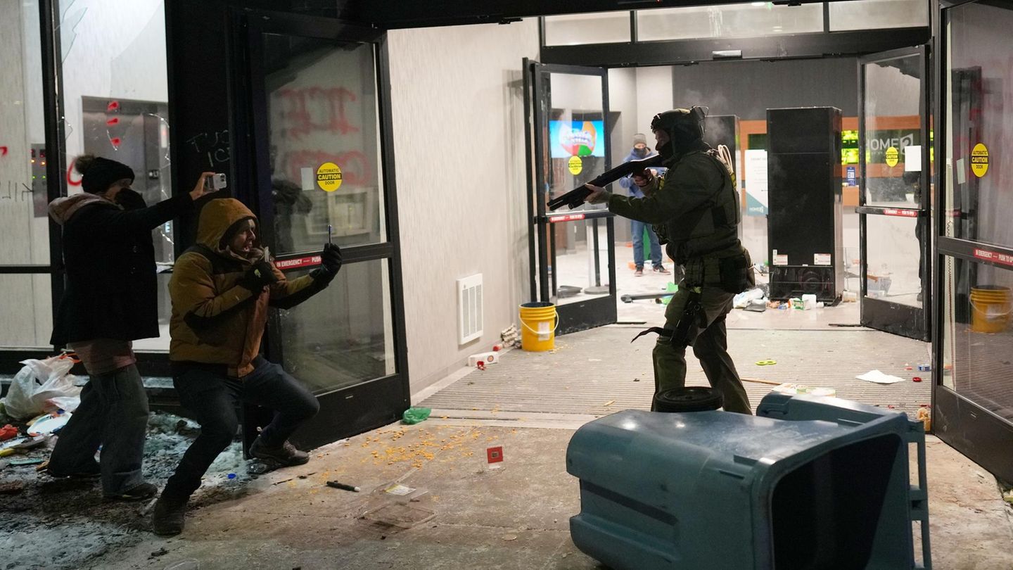 Dennoch gehen die Razzien weiter. Ein ICE Beamter richtet eine Waffe auf einen mutmaßlichen Migranten