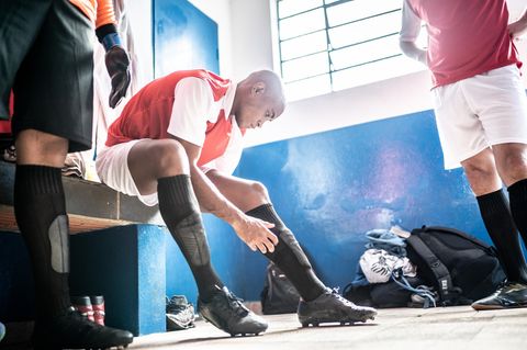Ein Fußballspieler schnürt sich in der Kabine die Schuhe