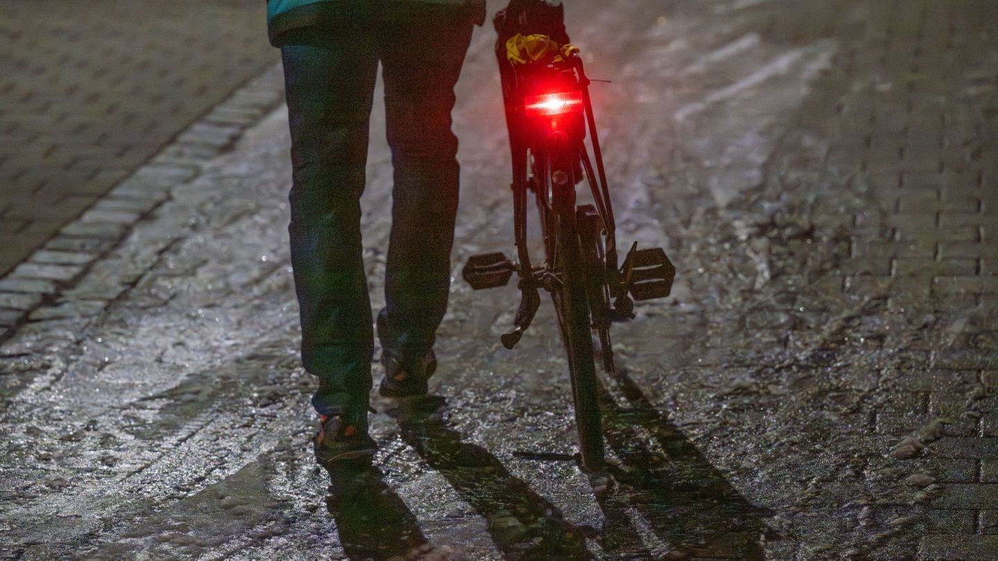 Ein Mann schiebt sein Fahrrad auf einer vereisten Straße. Foto: Armin Weigel/dpa