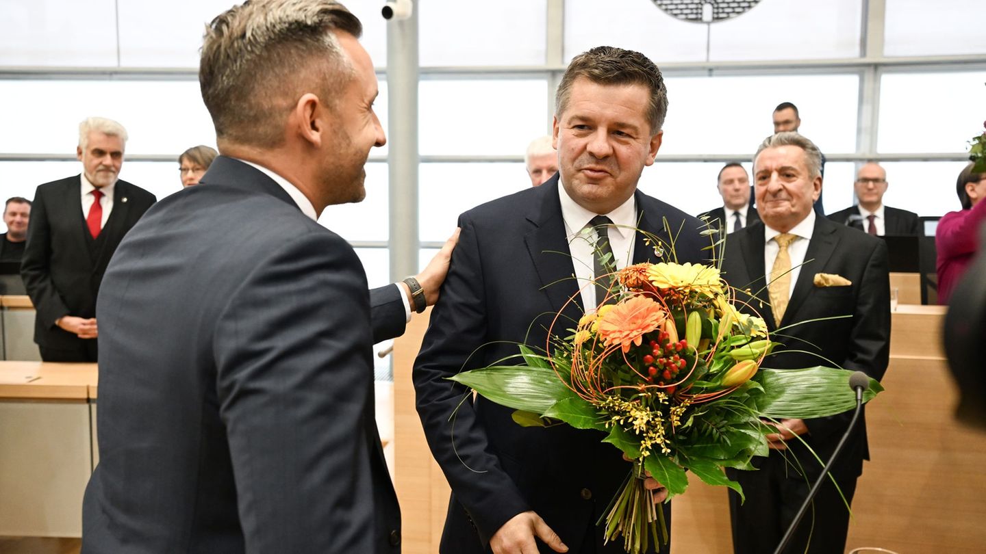 Sven Schulze bekommt Glückwünsche und einen Blumenstrauß vom AfD-Spitzenkandidaten Ulrich Siegmund. Foto: Hendrik Schmidt/dpa