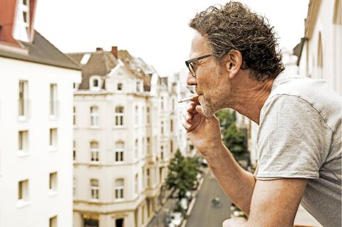 Mann steht auf dem Balkon und raucht, als Untermieter dürfte er nicht benachteiligt werden