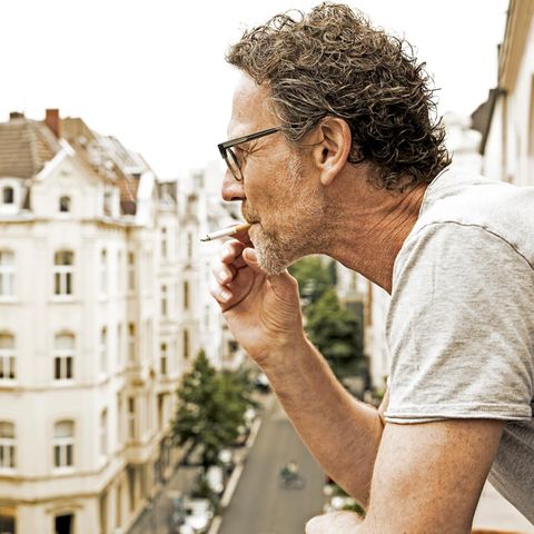 Mann steht auf dem Balkon und raucht, als Untermieter dürfte er nicht benachteiligt werden