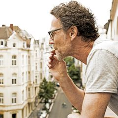 Mann steht auf dem Balkon und raucht, als Untermieter dürfte er nicht benachteiligt werden