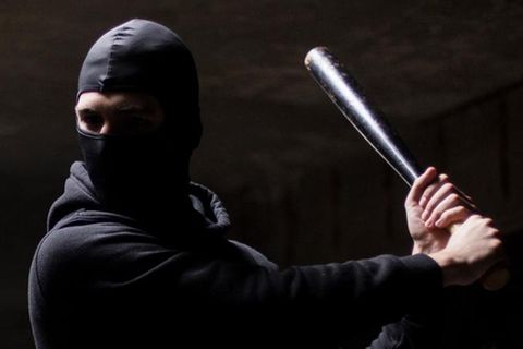 Mann mit Sturmhaube und Knüppel