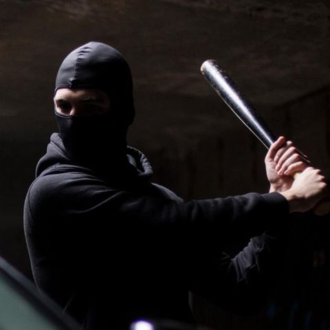 Mann mit Sturmhaube und Knüppel