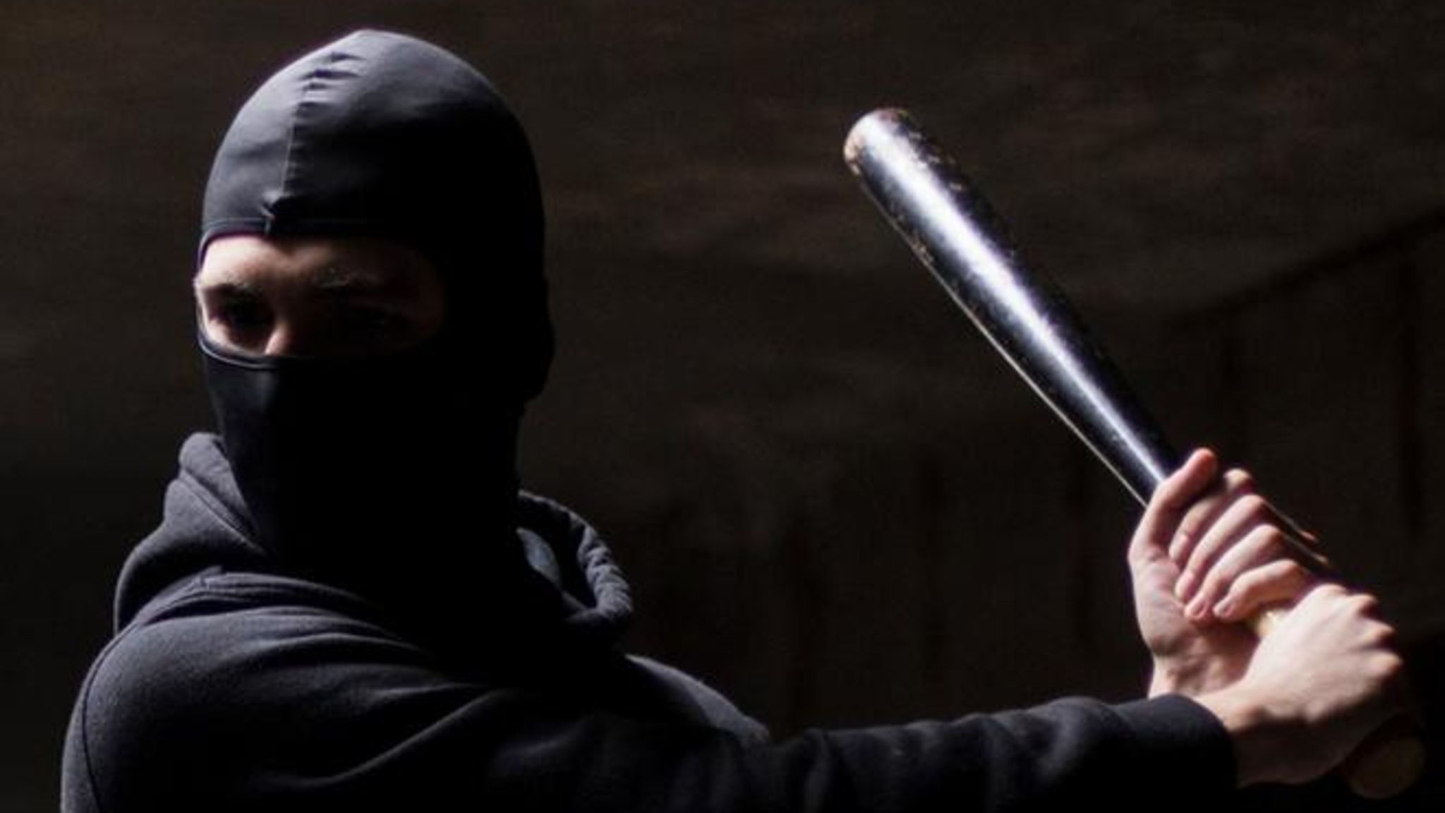 Mann mit Sturmhaube und Knüppel