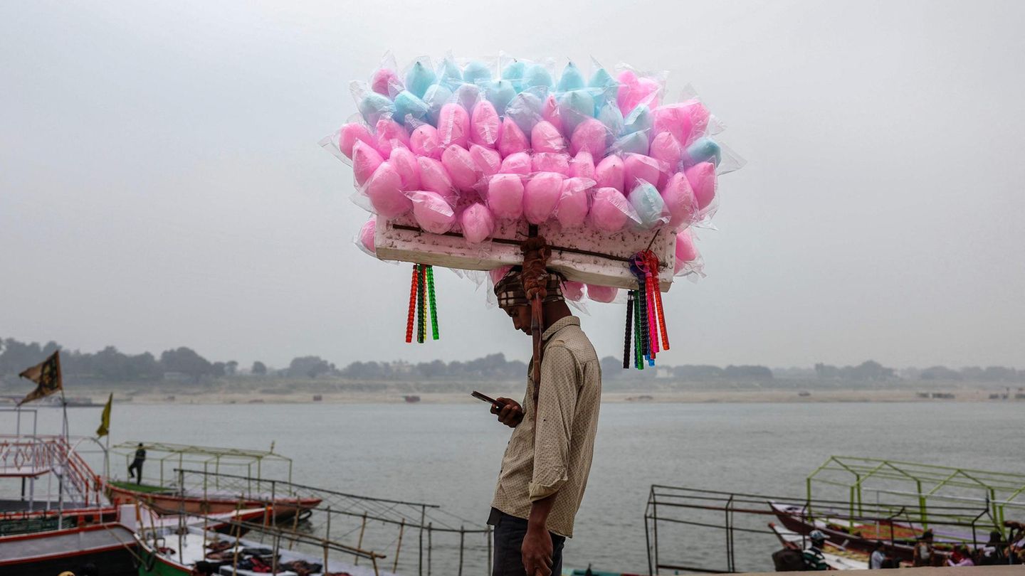 Varanasi, Indien. Einerseits sieht es aus, als trüge der junge Mann eine große Last auf dem Kopf – bis einem einfällt: Zuckerwatte ist nicht besonders schwer. Zumindest kann der Verkäufer relativ entspannt etwas auf seinem Handy machen. Und trotzdem: Ohne Kundschaft ist auch dieser Job kein Zuckerschlecken
