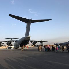 Eine Menschenschlange - Zivilisten - steht vor mehreren deutschen Militärflugzeugen