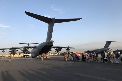 Eine Menschenschlange - Zivilisten - steht vor mehreren deutschen Militärflugzeugen
