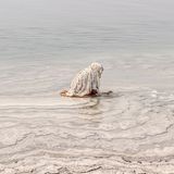 Am Ufer des Toten Meeres, in Jordanien, hockt eine Frau im flachen Wasser und tastet nach Salzsteinen. Beinahe entrückt erscheint die Szene und sie ist Teil einer Jahrtausende alten Tradition: Den Mineralen des hypersalinen Sees wird eine reinigende und heilende Wirkung zugeschrieben. Das Salz soll die Haut beruhigen, die Muskeln entspannen, kleine Wunden versiegeln. In Jordanien gehören Rituale der Pflege und Reinigung für viele zum Alltag, wobei sie heute auch in die Wellnessindustrie und den Tourismus reichen.   Die Aufnahme ist Teil des internationalen "Walk of Water"–Fotowettbewerbs von UNESCO und Onewater. Die ausgezeichneten Bildgeschichten zeigen, wie eng Wasser mit Identität und Kultur verwoben ist – von rituellen Gesten bis zum alltäglichen Überleben