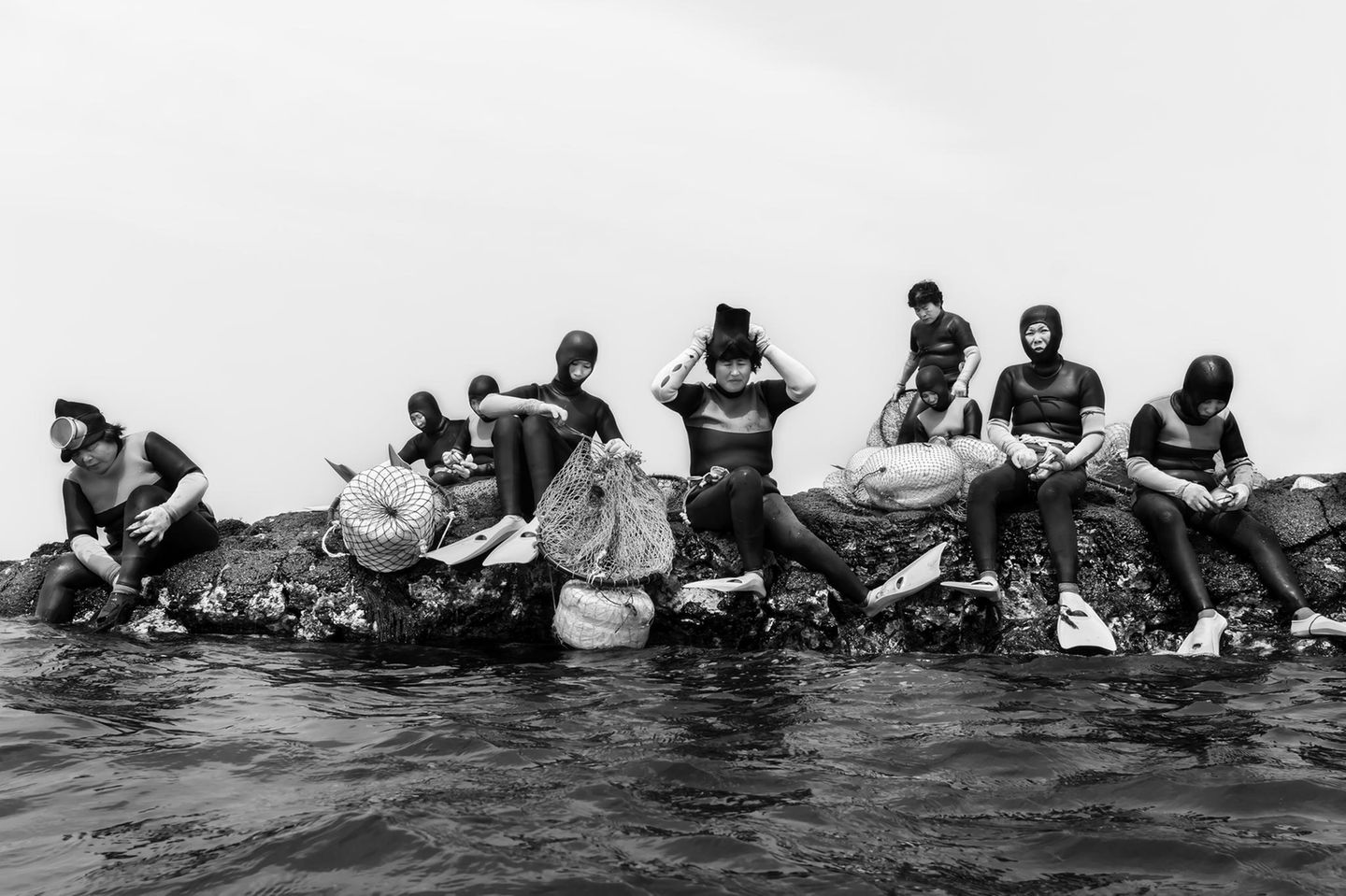 In der südkoreanischen Provinz Jeju arbeiten die Haenyeo: Taucherinnen, die sich ohne Sauerstoffflaschen in die blaue Tiefe begeben. Der Moment vor dem Abtauchen wirkt ruhig: Die Frauen sitzen auf dem Fels, prüfen Netze, Flossen und Masken, sammeln Kraft. Doch ihr Handwerk verlangt Härte und Präzision. Unter Wasser halten sie minutenlang die Luft an, navigieren durch Strömungen, lesen das Meer und ernten Seeohren, Seeigel oder Algen. Das charakteristische Pfeifen beim Auftauchen, "Sumbisori" genannt, ist zugleich Atemtechnik und Lebensversicherung. Seit Jahrhunderten wird das Wissen weitergegeben; heute ist es bedroht, durch Überfischung, den Klimawandel und das zunehmend hohe Alter vieler Taucherinnen. In diesem Porträt sammelt sie sich, die ganze Konzentration einer Kultur, die vom Rhythmus des Ozeans lebt