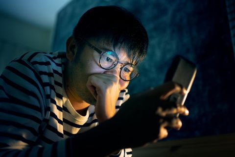 Ein junger Mann schaut besorgt auf sein Handy (Symbolbild Ex-Freund oder Ex-Freundin kontaktieren)