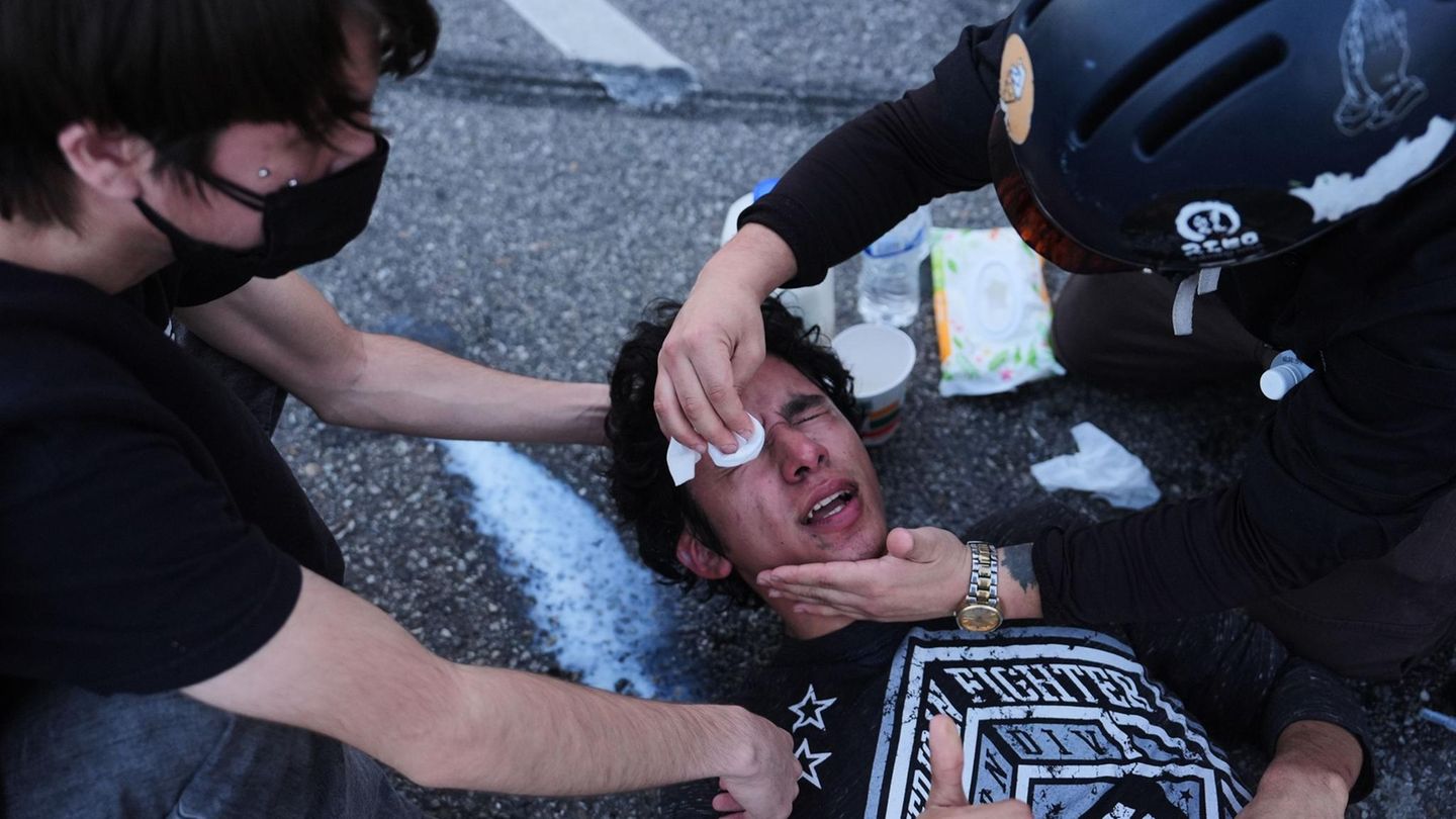 Anti-Ice Demo in den USA: Demonstrant liegt auf Boden, zwei Menschen helfen, ihm seine Augen auszuwaschen