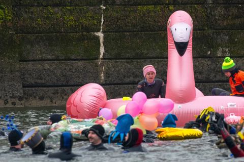 Teils bunt kostümiert schwimmen in und auf der eiskalten Donau Rettungsschwimmer. Foto: Stefan Puchner/dpa