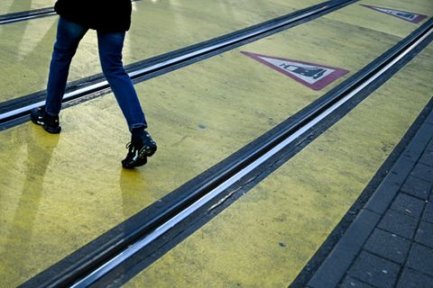 Eine Frau überquert Straßenbahngleise in Frankfurt.