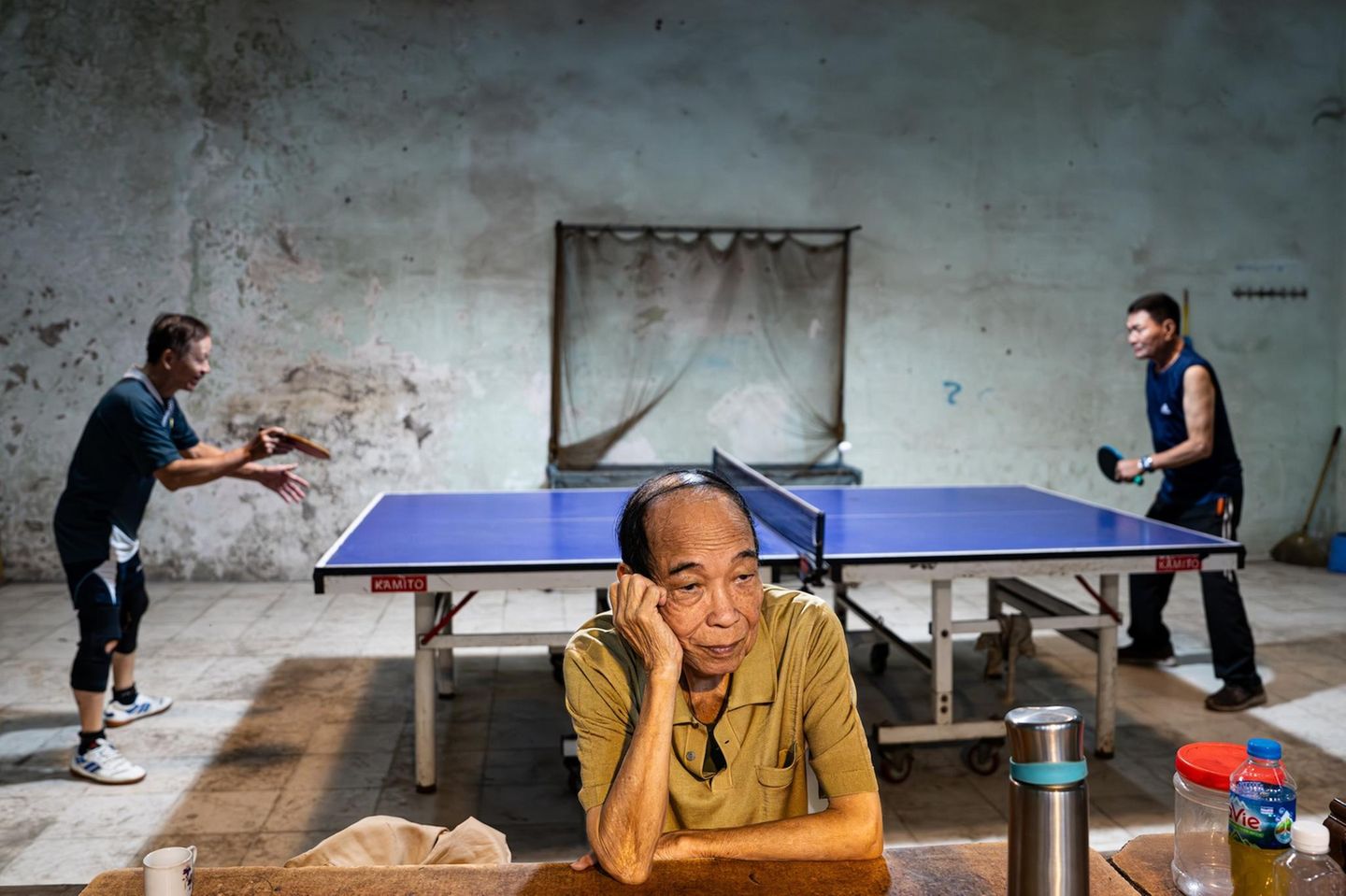 Hängt er seinen Gedanken nach, während zwei pensionierte Offiziere Tischtennis spielen? Oder ist er genervt vom lebhaften Match hinter seinem Rücken? Was den Mann im Vordergrund beschäftigt, bleibt offen – Fotograf Rahsan Firtina verrät es nicht. Doch gerade der Kontrast belebt sein Porträt einer Alltagsszene in Hanoi und verleiht dem Bild dazu einen Hauch von Komik
