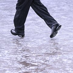 Eine Person läuft über einen vereißten Gehweg in Berlin (Symbolbild Wetter)