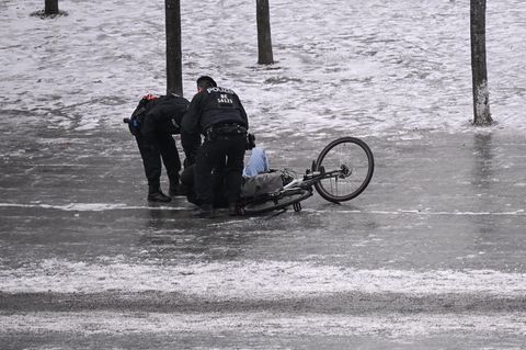 Polizisten helfen einem gestürzten Radfahrer (Symbolbild Wetter)