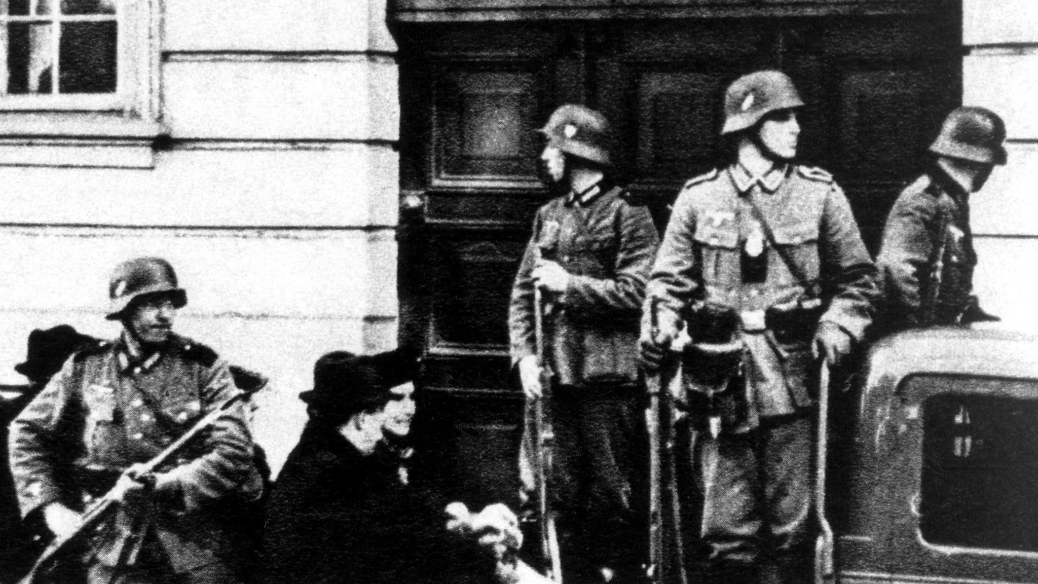 Bewaffnete Uniformierte mit Stahlhelmen vor einer Eingangstür; schwarz-weiß Aufnahme; NS-Zeit