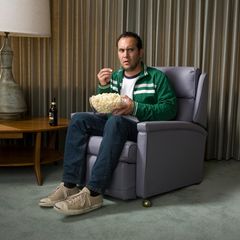 Ein Mann sitzt in einem Sessel und schaut unangenehm