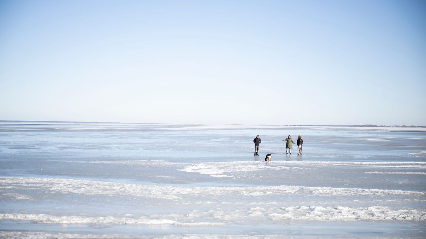 Menschen erkunden an der Küste die vergänglichen Eiswelten. Foto: Philip Dulian/dpa