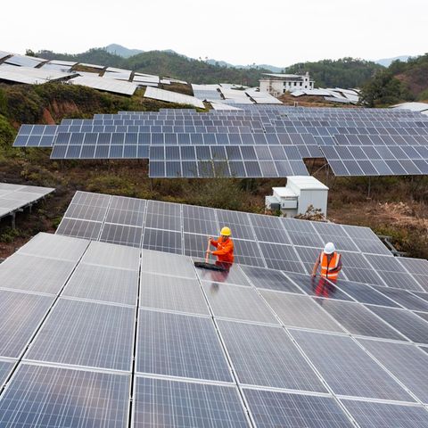 zwei Arbeiter putzen die Solarzellenoberfläche